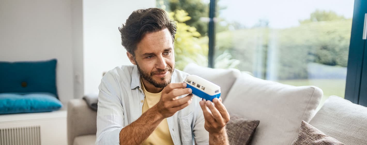 Ein Mann sitzt auf dem Sofa und schaut ein Mini Auto an.