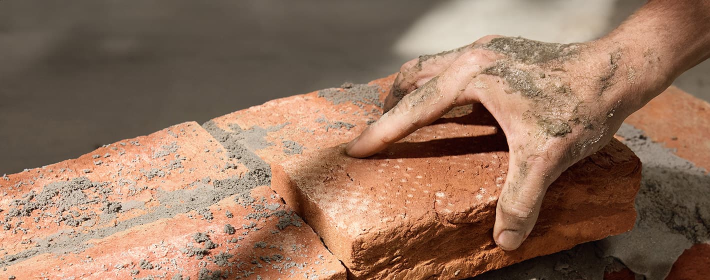 Ein passender Ziegelstein wir in eine Mauer gesetzt.